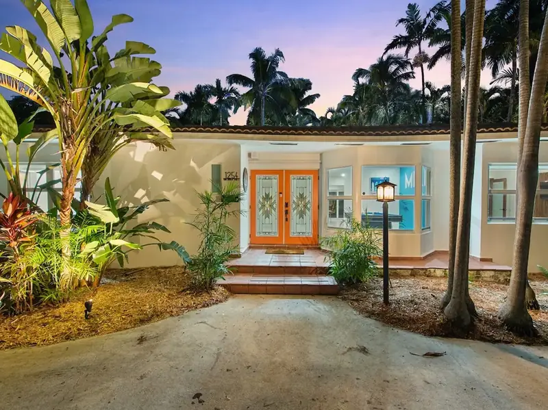 Tropical single-family home with a lit entrance at dusk, managed by Beach Vibes in Hollywood, FL