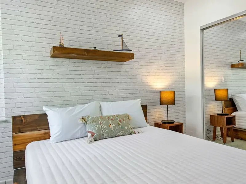 Bedroom with a queen bed and white brick wall