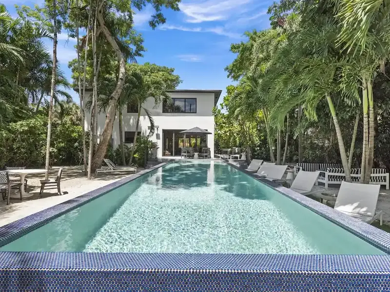 Long pool surrounded by palm trees at a vacation home we manage